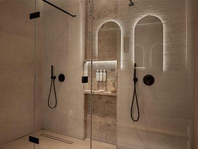 Nowoczesny, minimalistyczny prysznic hotelowy z przegrodą ze szkła, białymi ścianami i czarnymi armaturami.