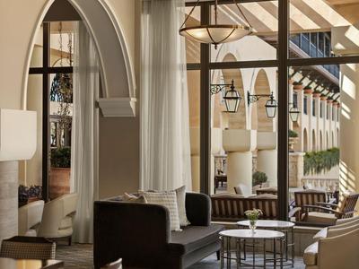 Elegancki salon hotelowy z wygodnymi fotelami, nowoczesnym oświetleniem i dużym oknem łukowym.