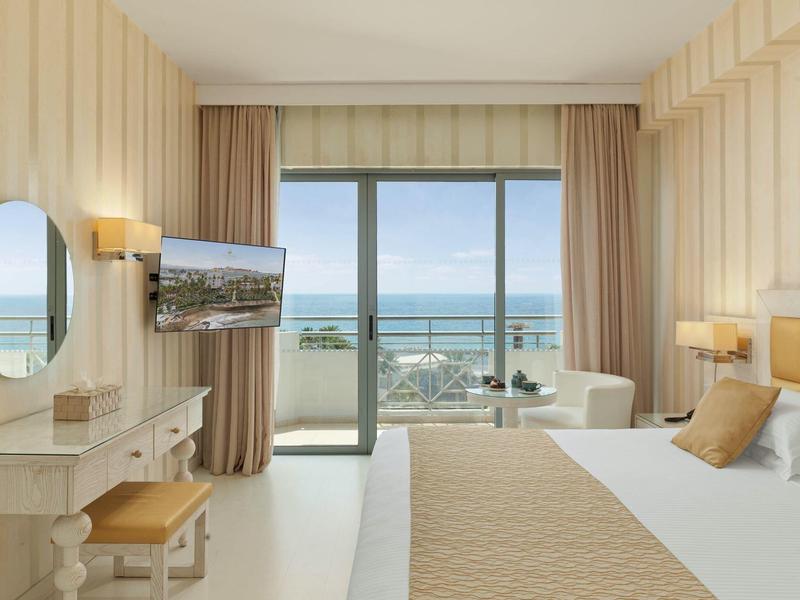 Helles Schlafzimmer mit großem Fenster, Meerblick, Doppelbett und moderner, heller Einrichtung.