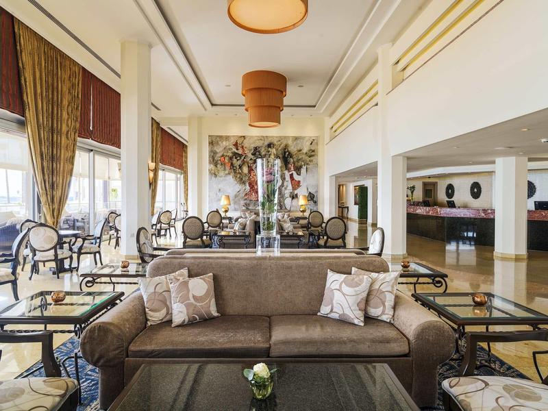 Großes, elegantes Wohnzimmer mit brauem Sofa, dekorativen Kissen und antiken Stühlen.