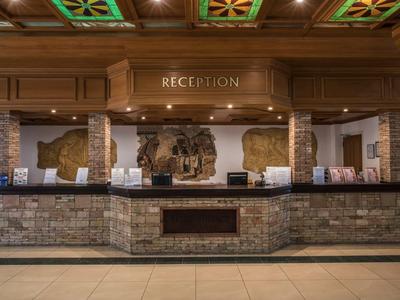 Rezeption mit rustikalem Holz- und Stein-Design, dekorativen Deckenfeldern und warmem Licht.