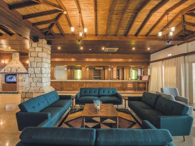 Großer Wohnraum mit blauen Sofas, Holzbalkendecke und Steinakzentwand, warm beleuchtet.