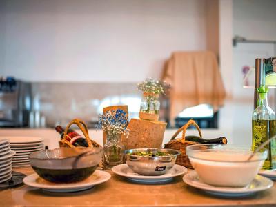 Verschiedene Schalen, Teller und Körbe mit Essenszubehör auf einem Holztisch in einer Küche.