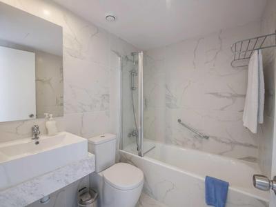 Moderner weißer Badezimmer mit Badewanne, Dusche, Waschbecken, WC und großem Spiegel.