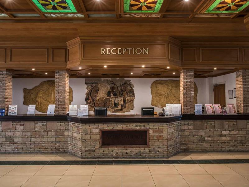 Rezeption mit rustikalem Holz- und Stein-Design, dekorativen Deckenfeldern und warmem Licht.