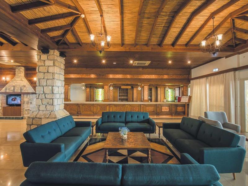 Großer Wohnraum mit blauen Sofas, Holzbalkendecke und Steinakzentwand, warm beleuchtet.