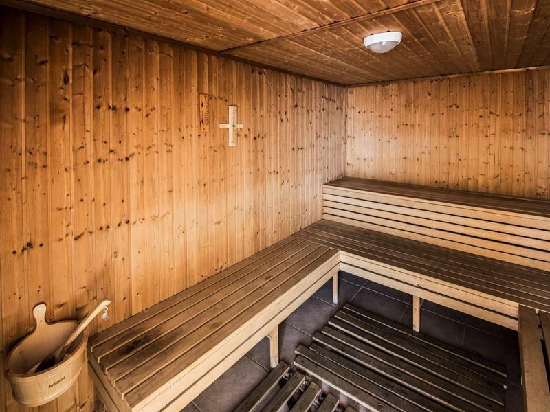 Innenraum einer Holzsauna mit Holzbänken, Holzeimer und Schöpflöffel, warmes Holzdesign.