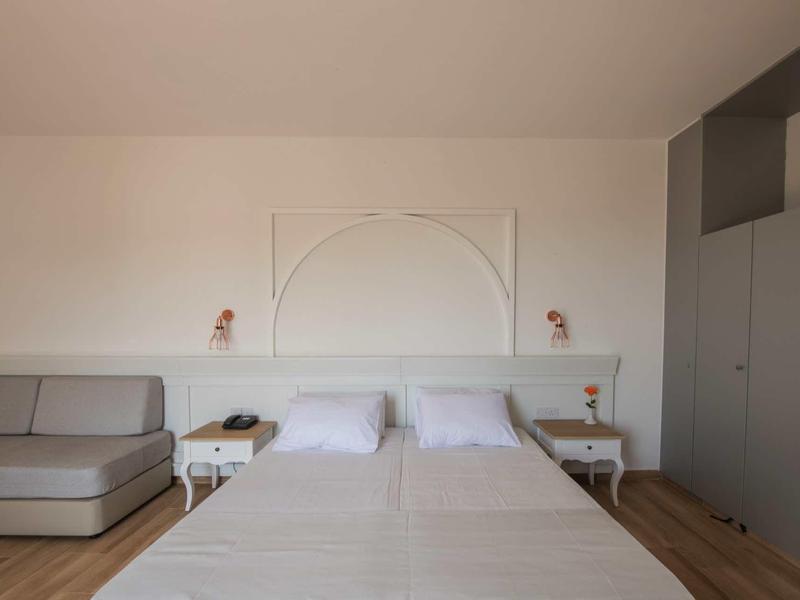 Modernes Schlafzimmer mit Doppelbett, grauem Sofa, Nachttischen und eingebauten grauen Schränken.