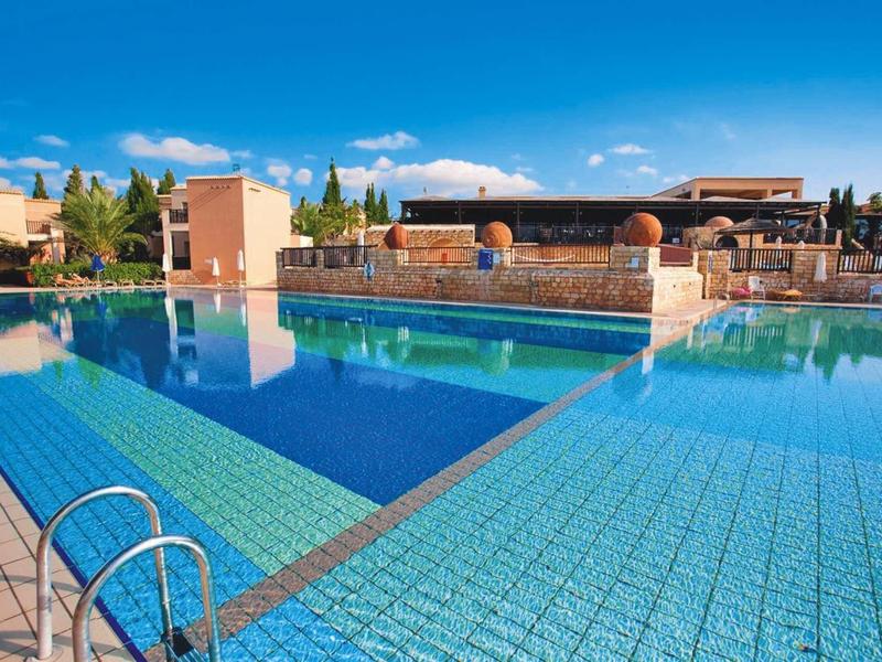 Klarer blauer Pool mit rutschigen Fliesen, umgeben von Gebäuden und blauem Himmel.