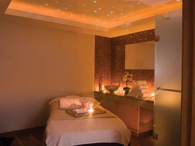 Příjemně osvětlená wellness místnost s masážním lůžkem a teplou atmosférou.