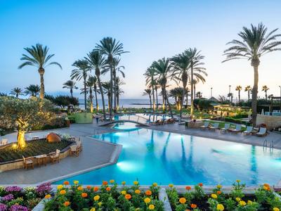 Hotel pool with palm trees and sunset in the background at a tropical vacation spot.