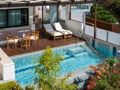 Modern outdoor pool with lounge chairs and seating area beside hotel rooms.