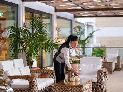Modern hotel lounge area with wicker furniture and candles on tables, decorated with large plants.
