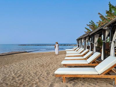 Beach with loungers and sunshades by calm sea under a clear blue sky.