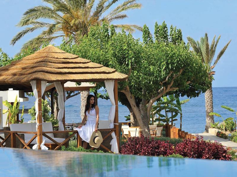 Landschaft mit Strand, blauer See, Palmen, grünen Bäumen und Holzhütte mit Strohdach.