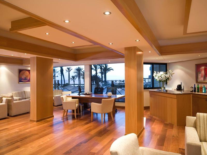 Elegantes Wohnzimmer mit Holzboden, modernen Möbeln und Blick auf Palmen und Meer.