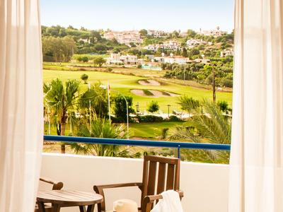 Balcone con sedia, tavolo e vista su un campo da golf in una zona di vacanza soleggiata.