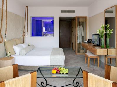 Camera d'hotel moderna con letto matrimoniale, scrivania, zona soggiorno e TV.