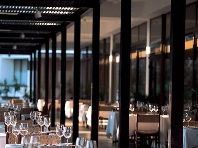 Restaurante elegante con mesas preparadas y techo moderno de listones de madera.