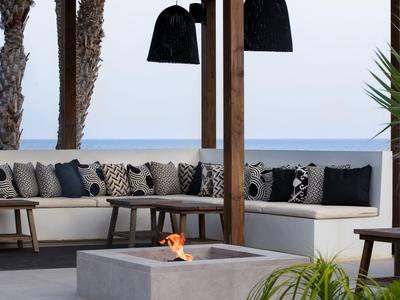 Moderne Terrasse mit gemütlicher Sitzecke, Feuerstelle und Blick aufs Meer.