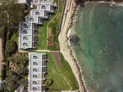 Luftaufnahme eines Hotels am Wasser mit Reihenbungalows und grünem Rasen.