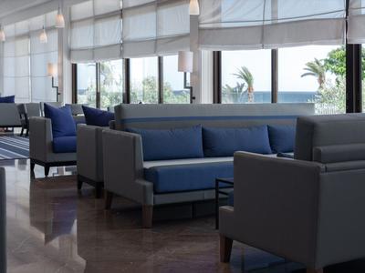 Helles, modernes Hotel-Lounge mit blauen und grauen Sofas und großer Fensterfront.