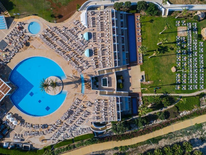 Luftaufnahme eines großen Pools mit Sonnenschirmen, Liegen und angrenzendem Gartenbereich.