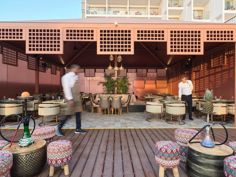 Outdoor-Café mit Holzboden, vielen Sitzplätzen, bunten Hockern und Schischa-Pfeifen.