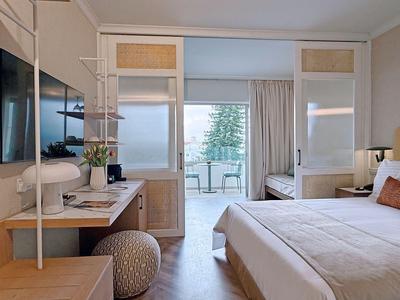 Camera d'hotel moderna con letto, scrivania e balcone con vista sul mare.