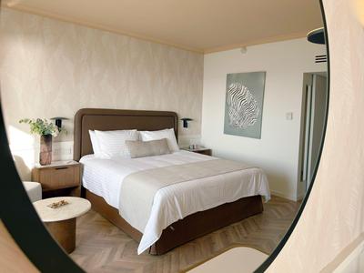 Modernes Schlafzimmer mit großem Bett, weißen Bettlaken, Nachttischen und minimalistischer Dekoration.