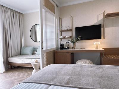 Helles Hotelzimmer mit modernem Schreibtisch, Fernseher und gemütlicher Sitzecke am Fenster.