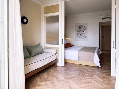 Helles Hotelzimmer mit Doppelbett und Sofabett, Holzboden und moderner Einrichtung.