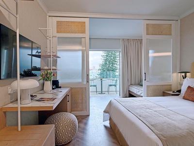 Modernes Hotelzimmer mit Doppelbett, Schreibtisch und Balkon mit Meerblick.