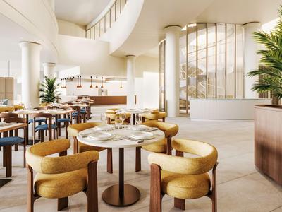 Area lobby di hotel moderna con tavoli rotondi, sedie confortevoli e decorazioni con piante.