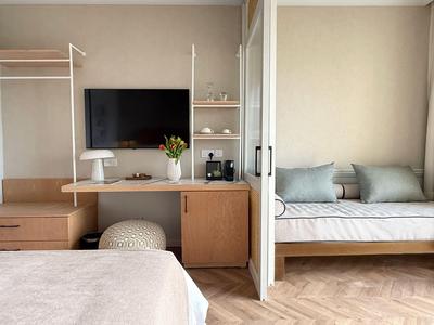 Camera d'hotel moderna con letto, scrivania, TV e divano.