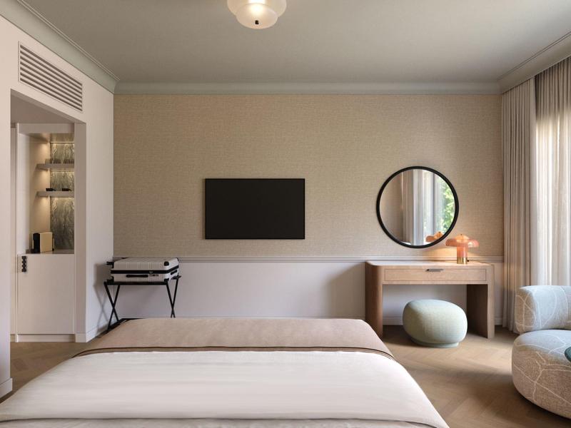 Modernes Hotelzimmer mit Doppelbett, Schreibtisch, rundem Spiegel und Sitzgelegenheiten.