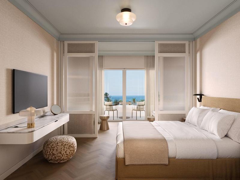 Helles Hotelzimmer mit Doppelbett, Meerblick und Balkon mit Sitzgelegenheiten.