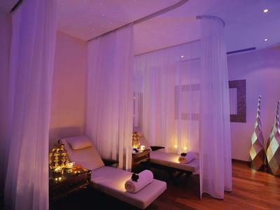 Ruhebereich mit weißen Vorhängen, Liegen und gedämpfter Beleuchtung in Hotelspa.