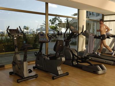 Palestra con attrezzi da esercizio davanti a grandi finestre con vista esterna.