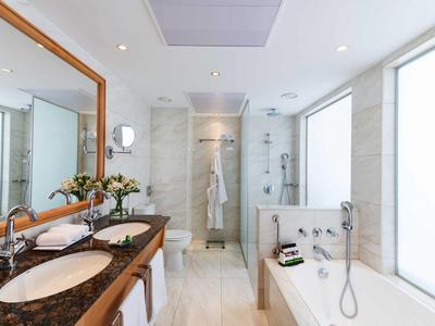 Bagno luminoso con doppi lavandini, ampia vasca da bagno e doccia separata.