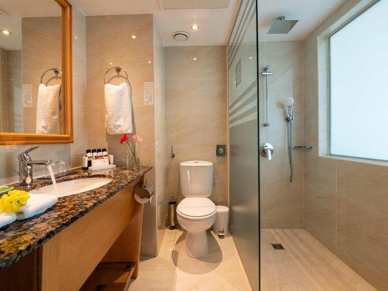 Moderne Badezimmer mit Toilette, Glasdusche, Granit-Waschtisch und hellem Wandspiegel.