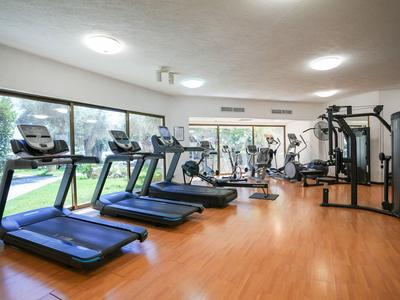 Moderner Fitnessraum mit Laufbändern und Kraftgeräten in einem hellen Hotelbereich.