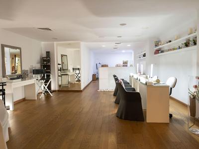 Heller, moderner Salon mit Holzboden, weißen Wänden und mehreren Arbeitsplätzen.