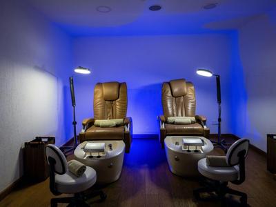 Zwei bequeme Pediküre-Sessel in einem entspannten, blau beleuchteten Spa-Raum.