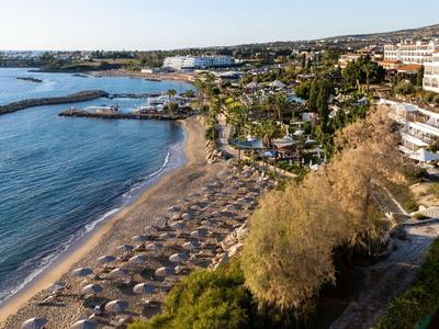 Langer Sandstrand mit Sonnenschirmen neben Hotelanlagen am Meer.
