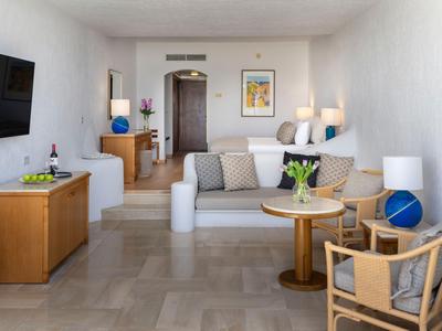 Helles Hotelzimmer mit Sofa, Sesseln und TV, moderne Einrichtung mit Holzmöbeln.