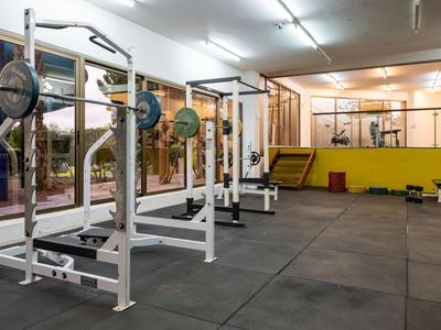 Leerer Fitnessraum mit Hantelbänken, Gewichten und Spiegelwand.