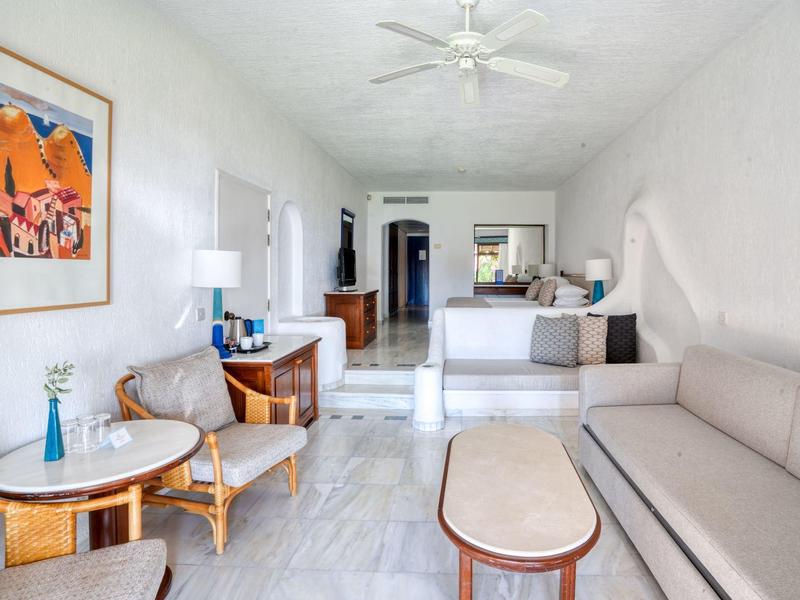 Helles Wohnzimmer mit grauem Sofa, Holzmöbeln, rundem Tisch und farbiger Kunst an der Wand.