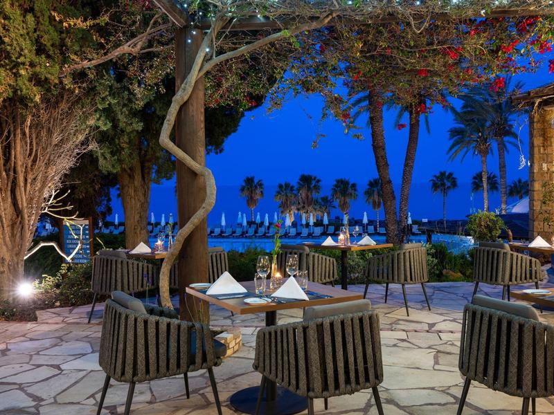 Terrassenplatz mit runden Tischen, Stühlen aus Holz, Marmorplatten und Landschaft bei Abenddämmerung.