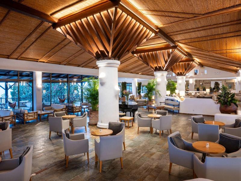 Helles, modernes Restaurant mit Holzdecke, weißen Säulen und stilvollen grauen Sitzmöbeln.